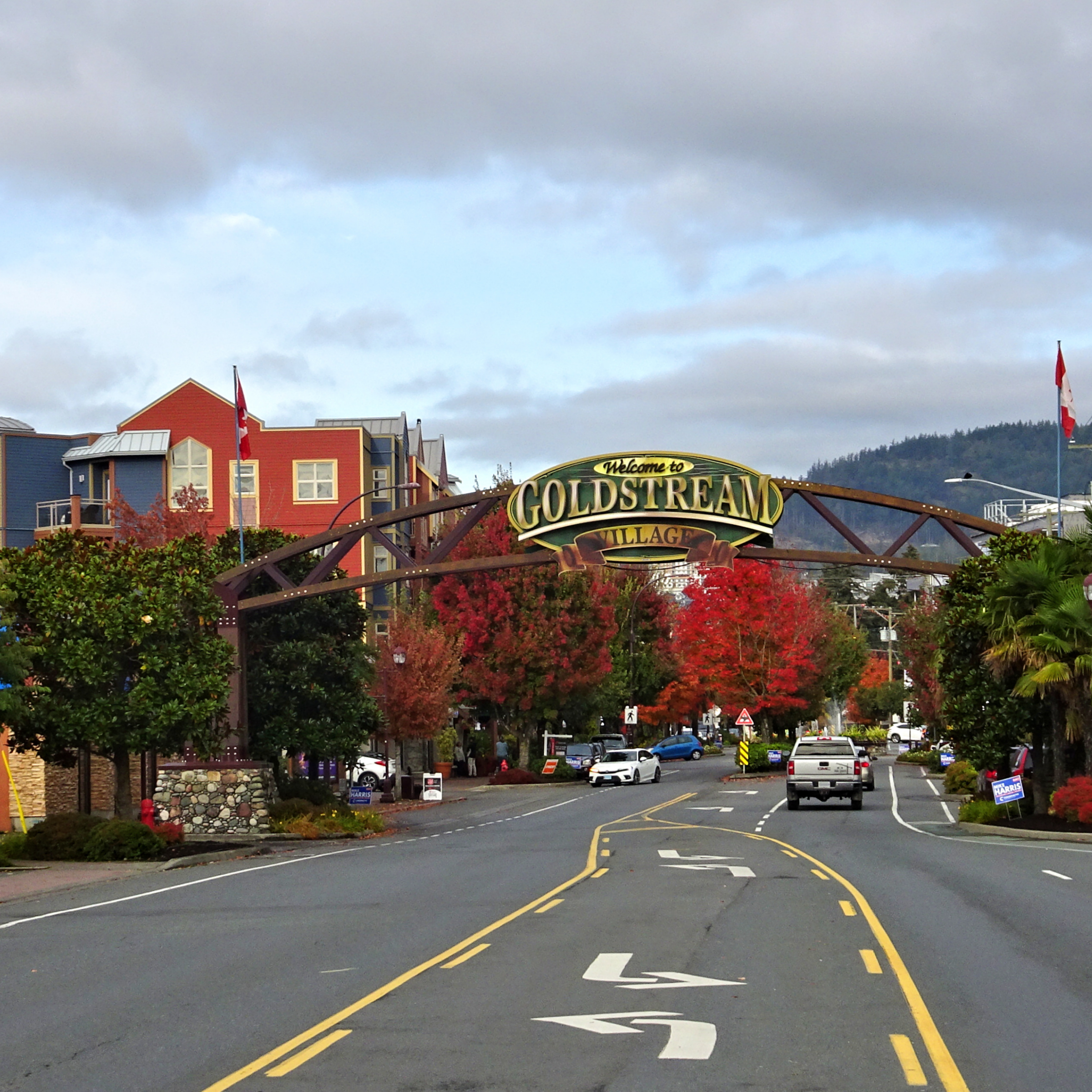 The Welcome to Goldstream Village arch over a Langford street lined with autumn trees