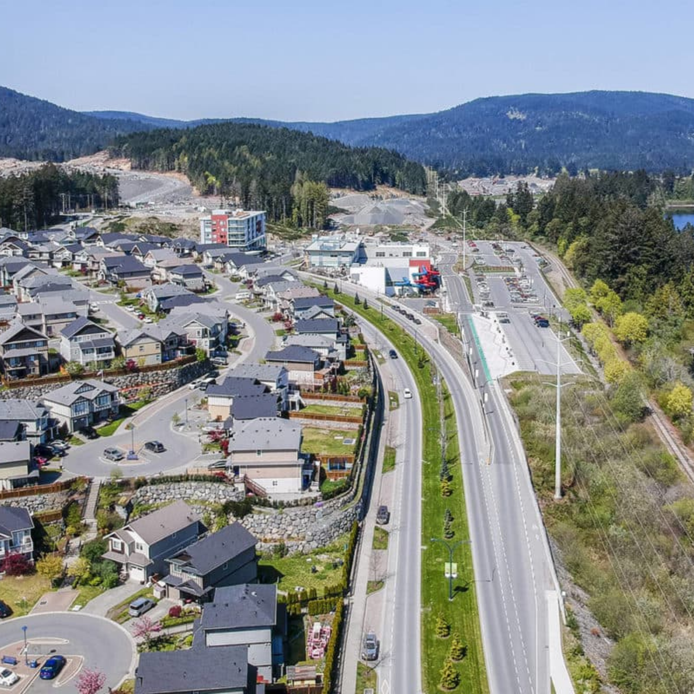 Aerial view of a Westshore neighbourhood beside a divided highway and forested hills